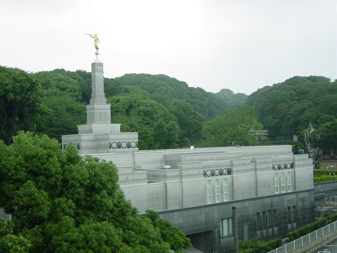 Fukuoka Japan Temple exterior, Angel Moroni spire, surrounded by green hills.