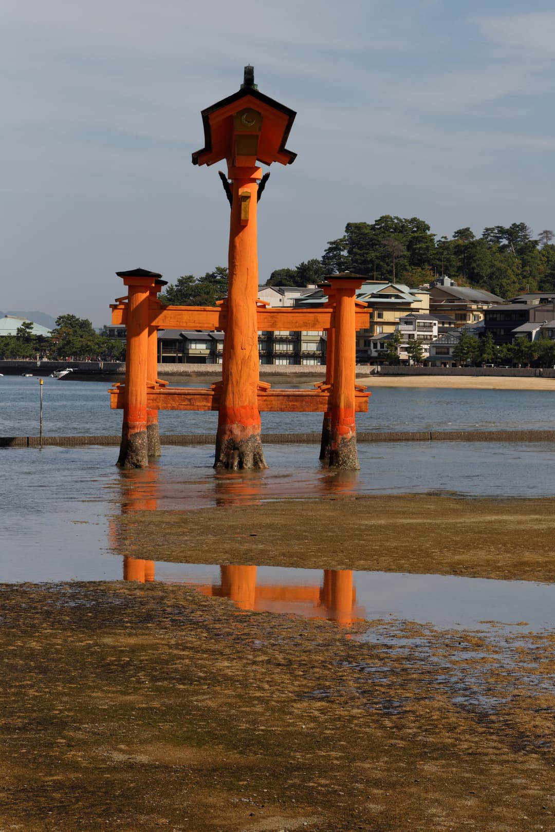 Side profile of the Itsukushima O-torii gate at low tide, daytime.