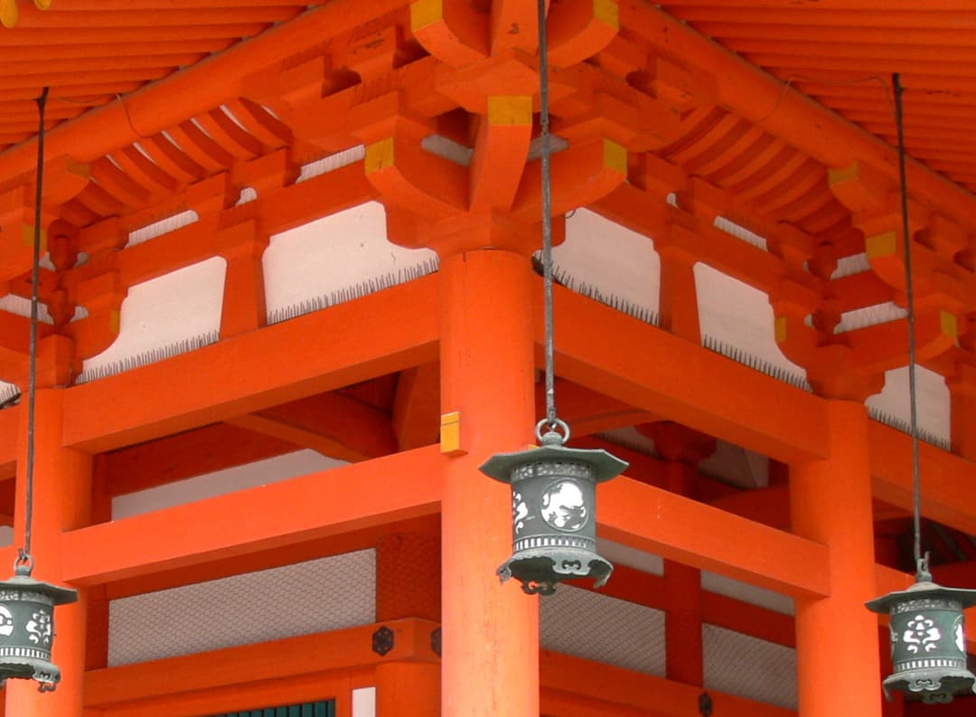 Detail of vermilion timber brackets and hanging lanterns.
