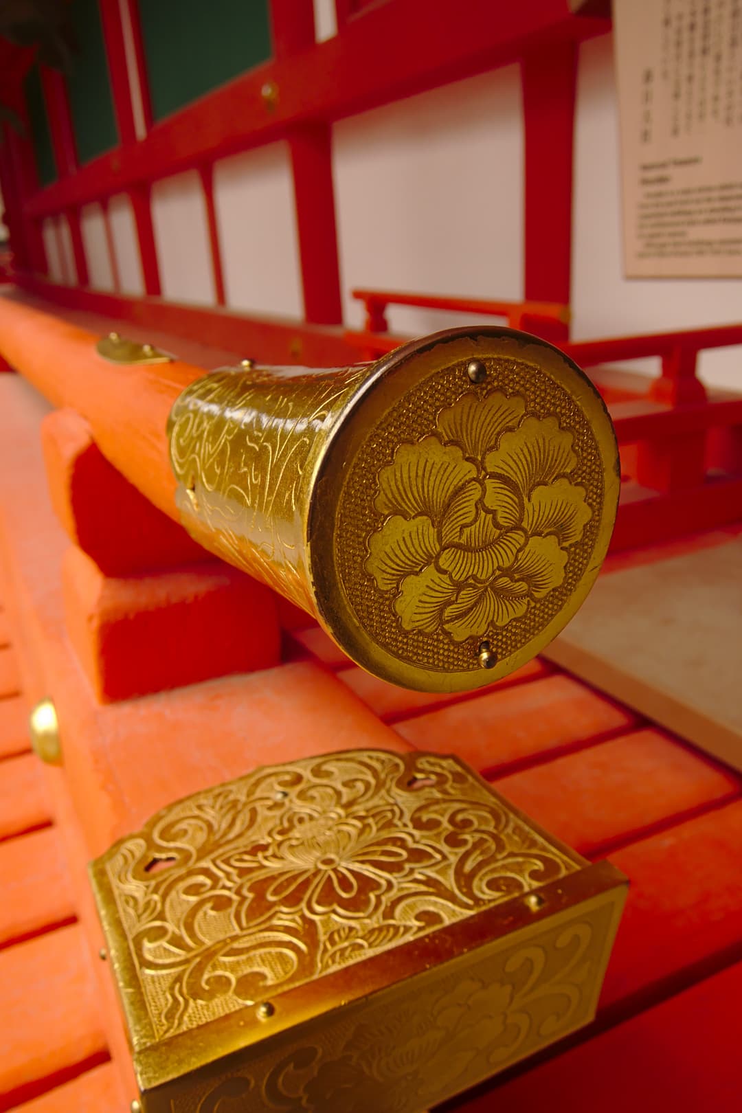 Close-up of ornate gilded metal fittings on a vermilion wooden railing