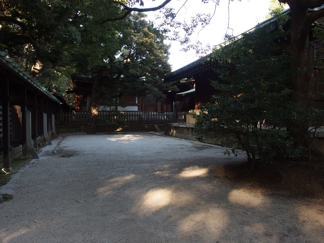 Dappled sunlight across a gravel courtyard at Meiji Shrine