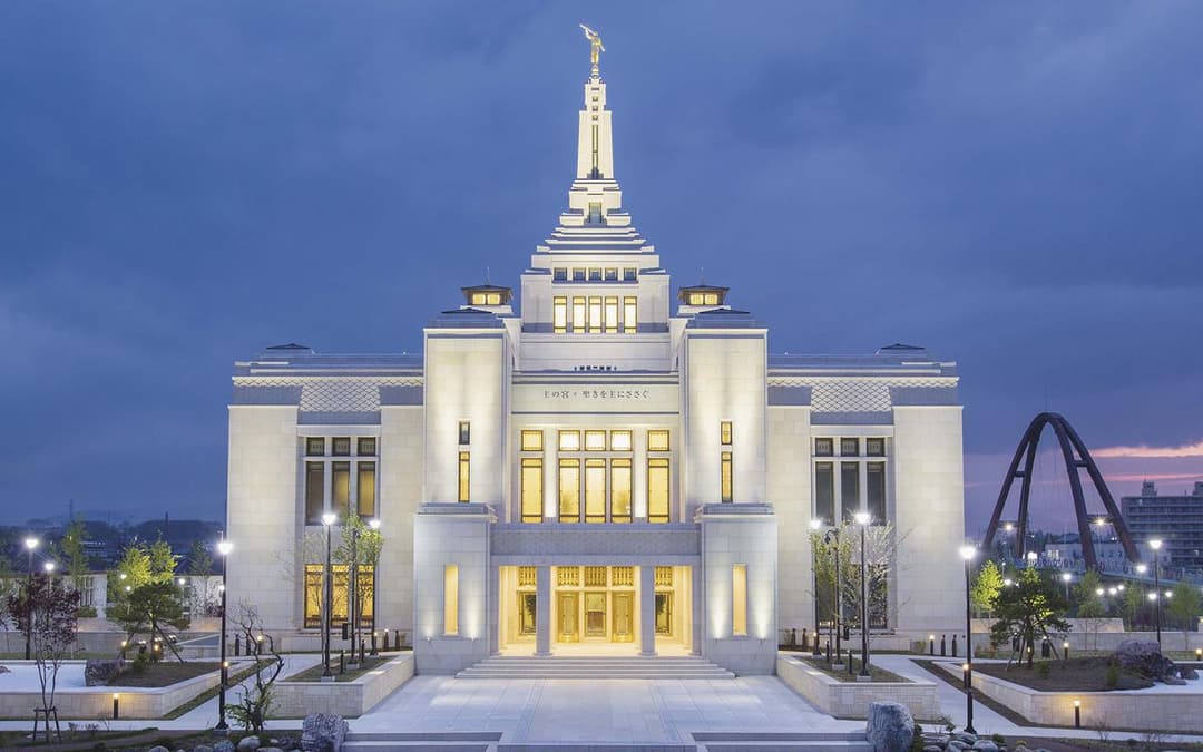 Front facade of the illuminated Sapporo Japan Temple at twilight.