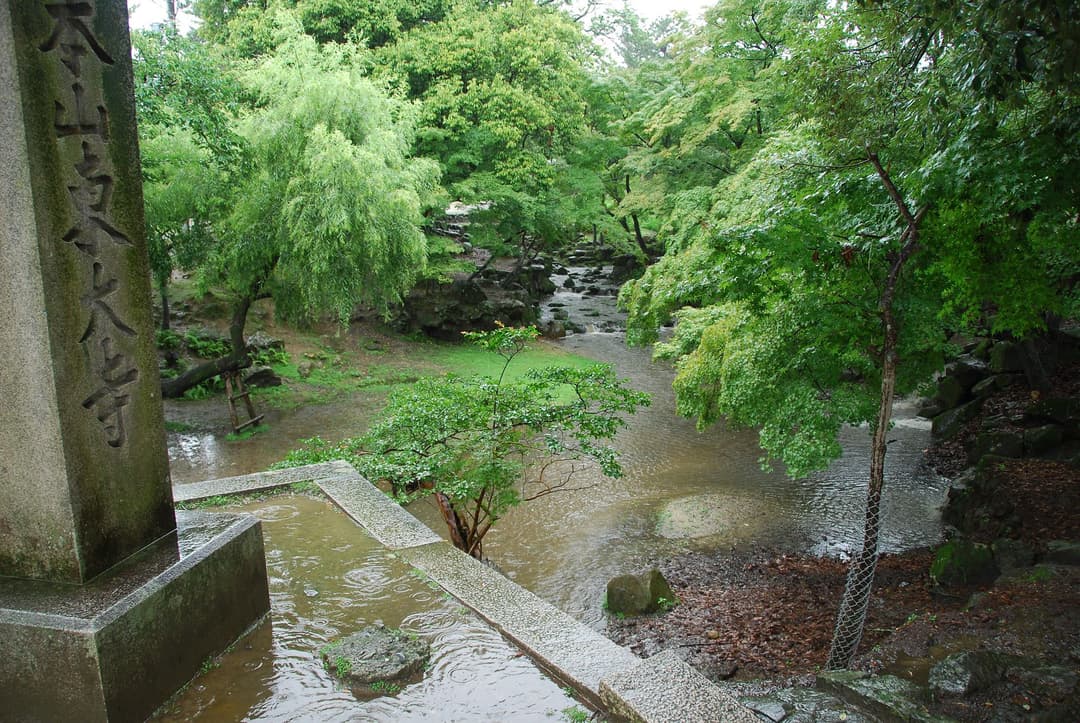 Rain falling over the wooded grounds and stream at Tōdai-ji