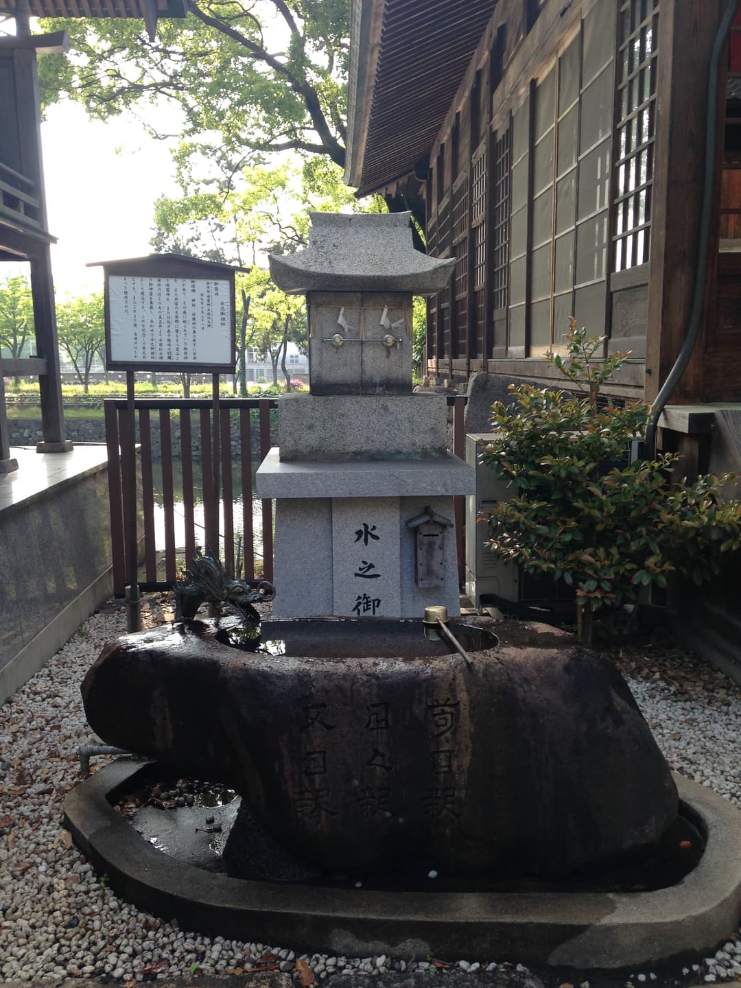 Stone purification water basin with dragon spout and small stone shrine.