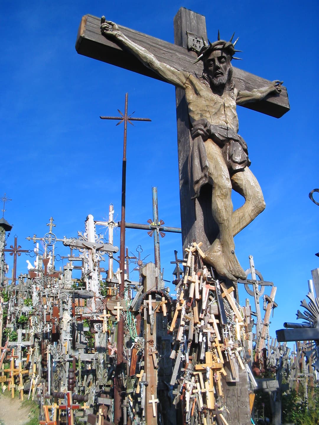 Low-angle view of a large carved wooden crucifix surrounded by crosses.