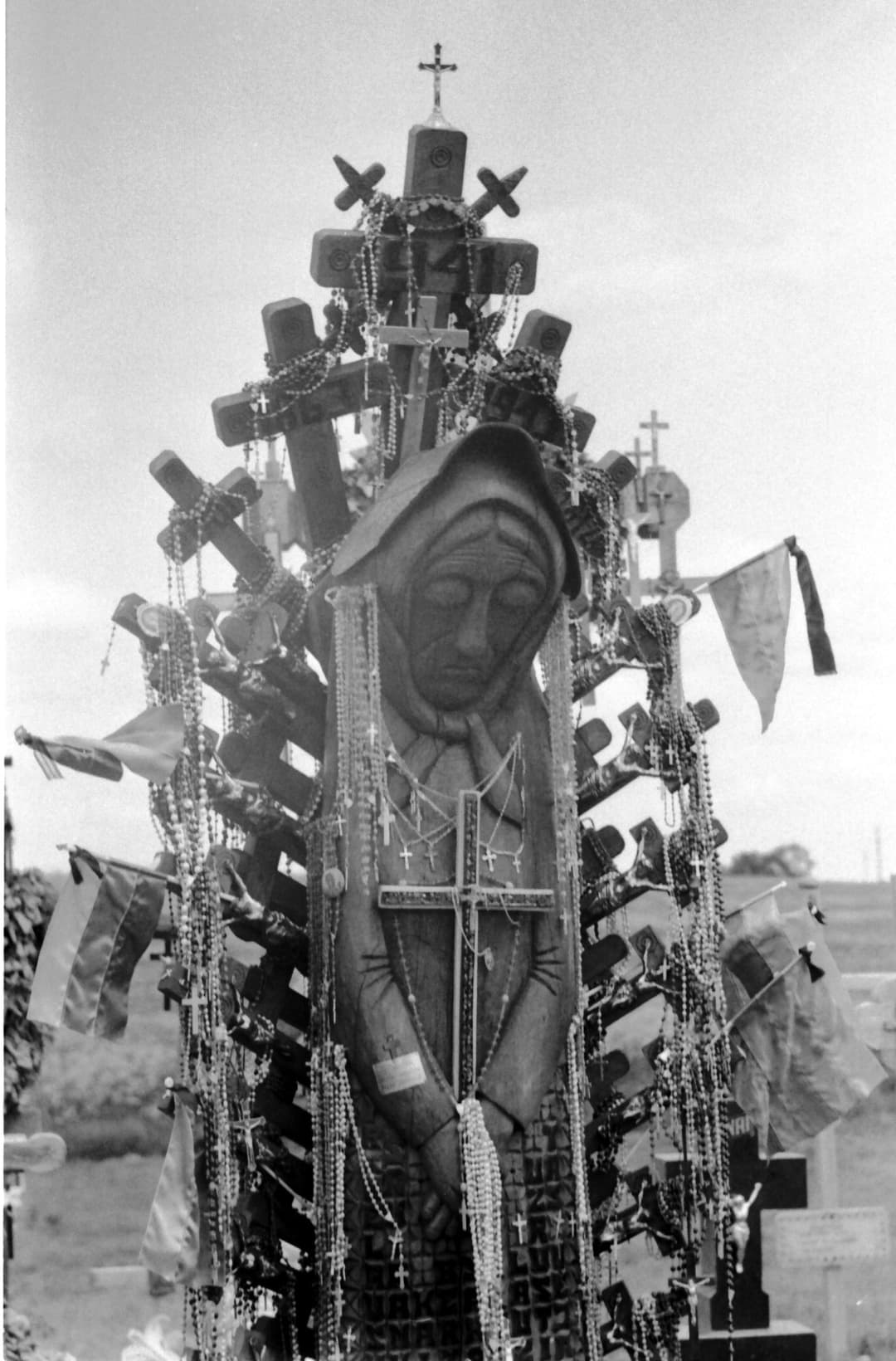 Carved wooden cross draped with rosaries at the Hill of Crosses