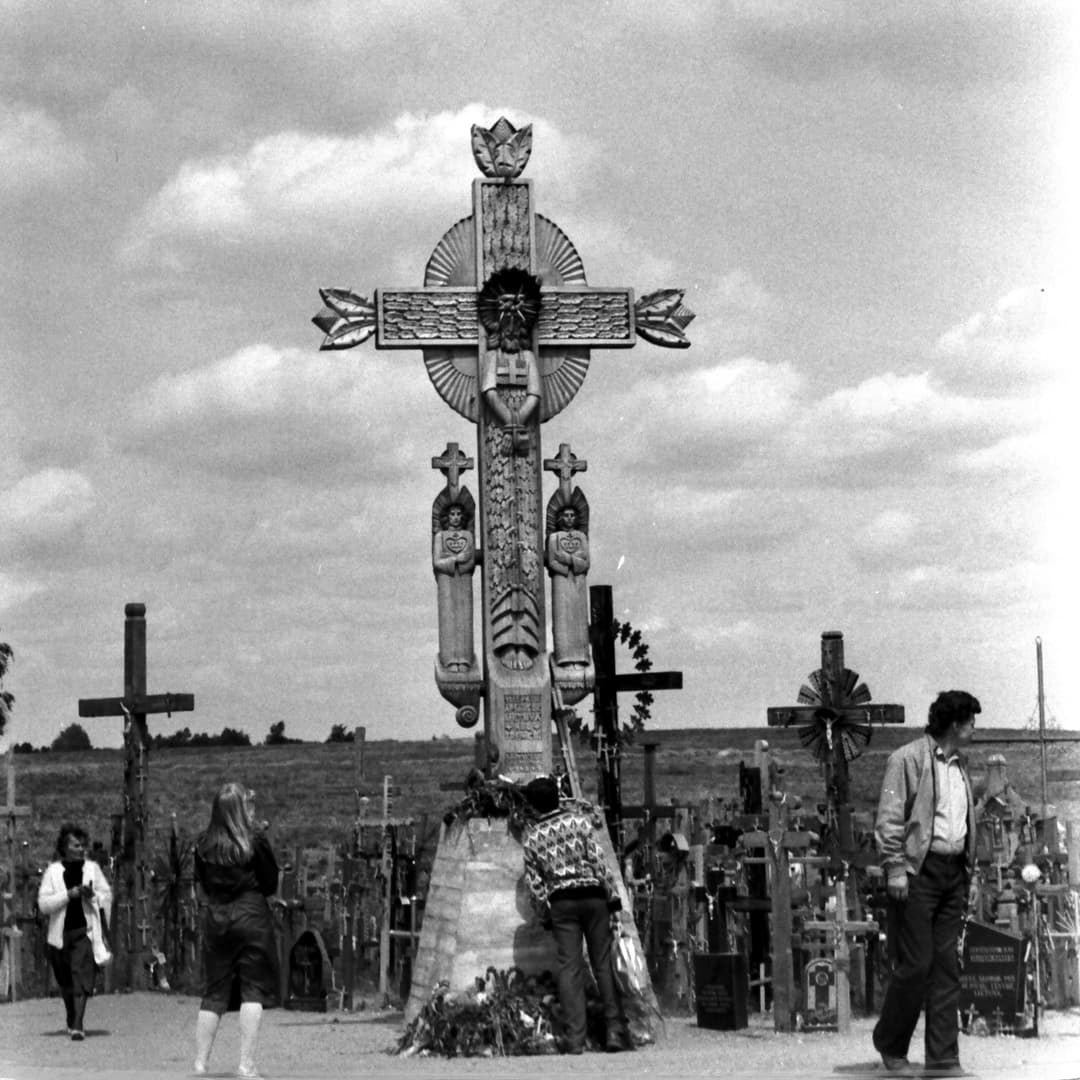 Monumental carved wooden cross and visitors at the Hill of Crosses.