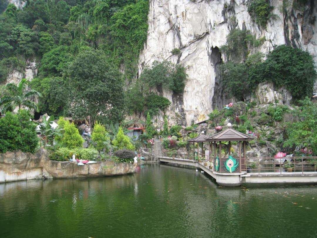 Pond with garden pavilions at the foot of the Batu Caves limestone cliffs