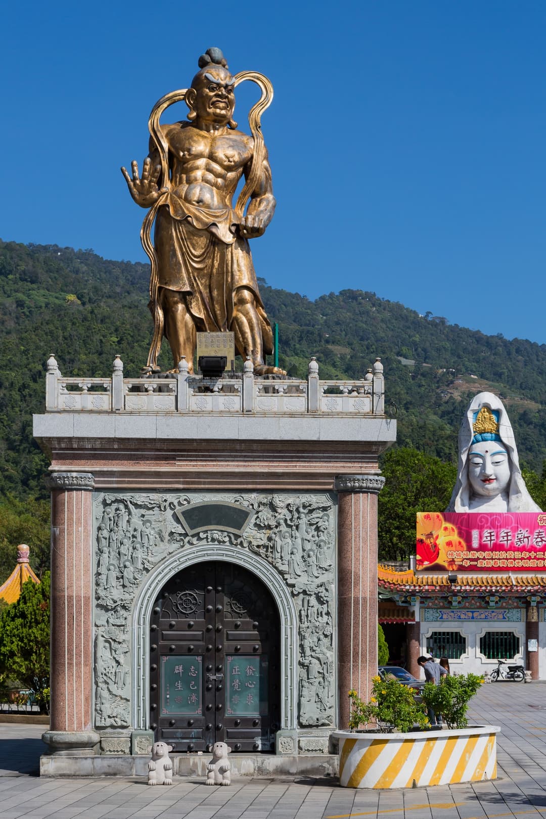 Golden temple guardian statue atop a carved pavilion at Kek Lok Si Temple.