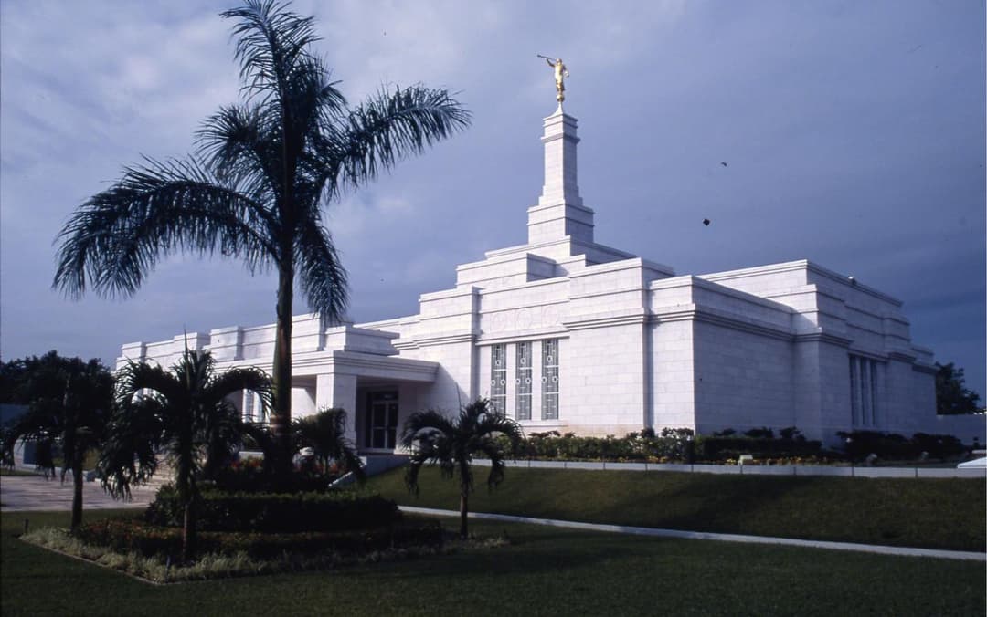 Wide exterior view of Mérida Mexico Temple with Angel Moroni and tropical gardens.