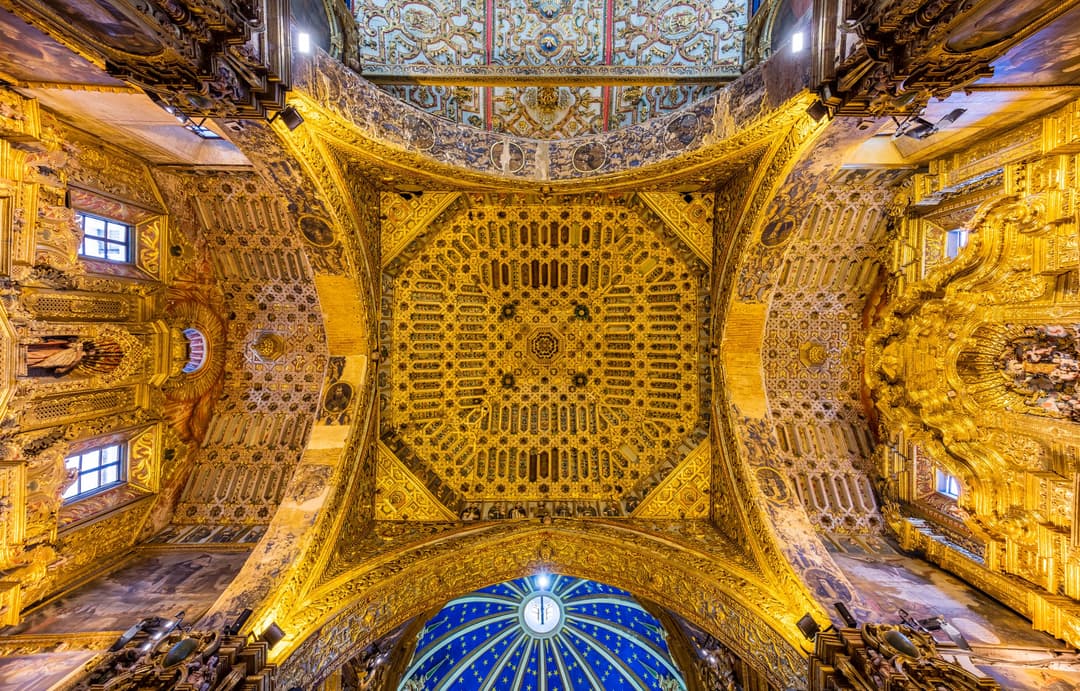 Interior view looking up at the ornate gilded ceiling and starry blue dome.