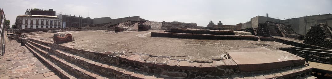 Panoramic view of stone platforms and carved serpent heads at Templo Mayor.