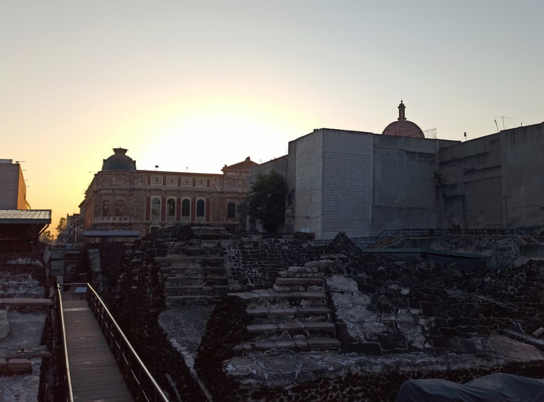 Templo Mayor archaeological site with historic buildings at dusk.