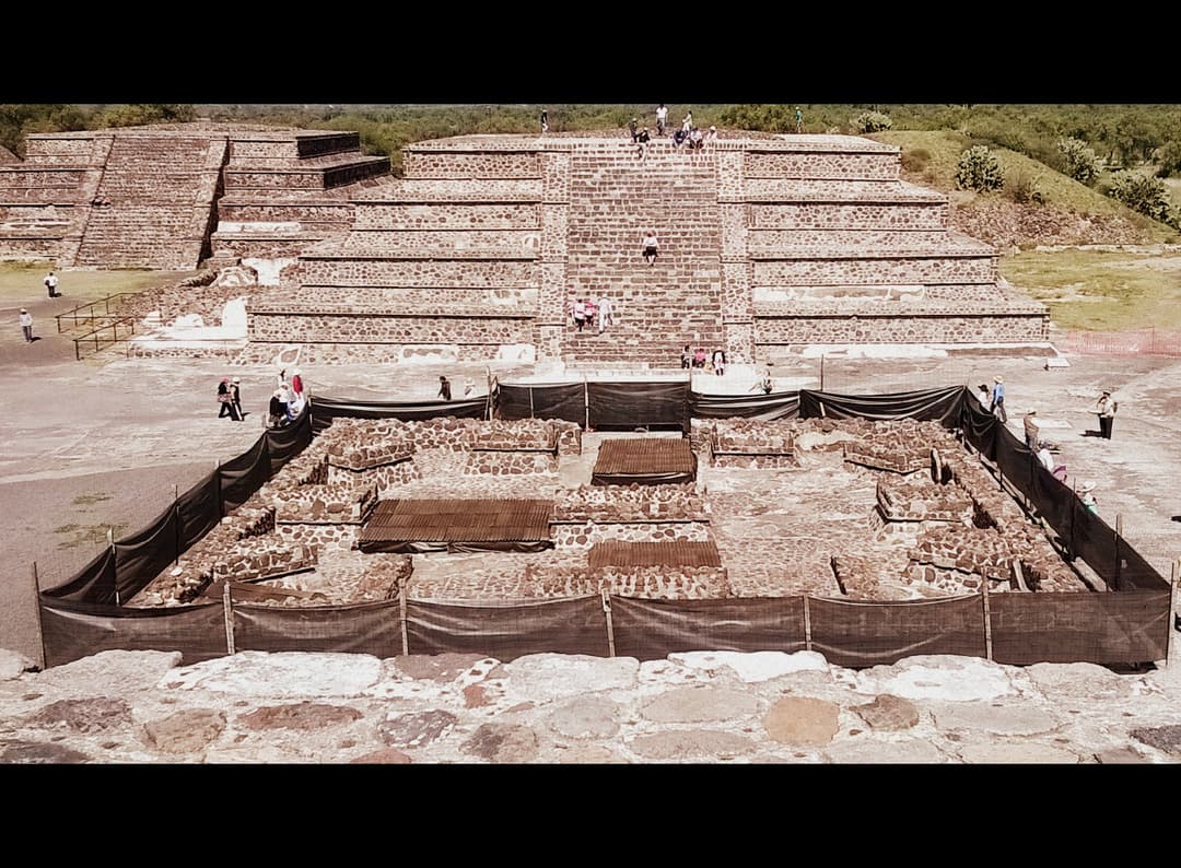 Elevated view of a stepped pyramid and excavated ruins at Teotihuacan.