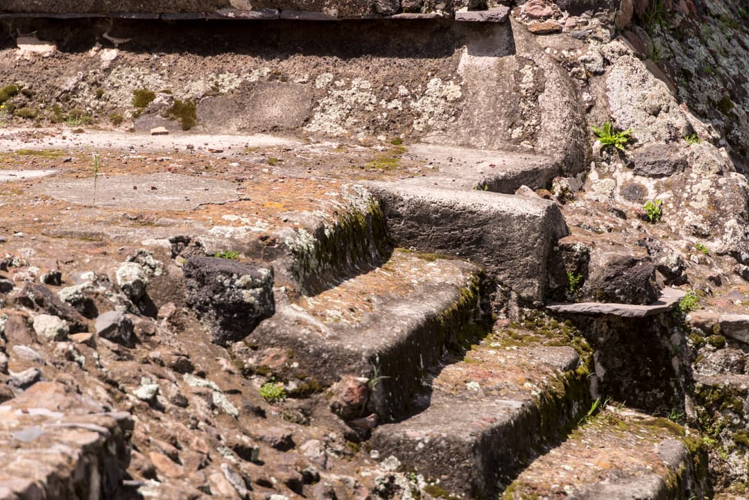 Close-up of weathered stone steps at Teotihuacan in bright sunlight.