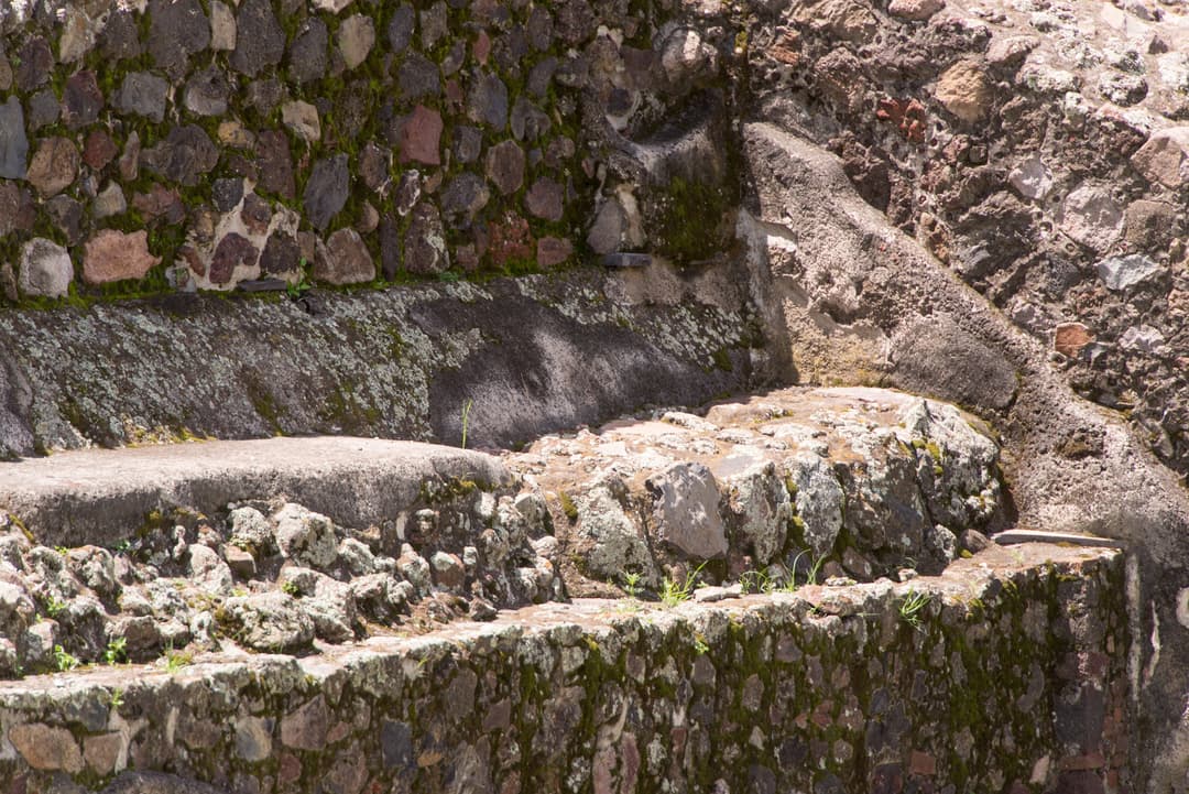 Close-up of weathered stone masonry terraces and moss in bright daylight.