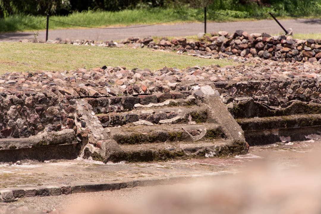 Low stone platform and steps on the grounds of Teotihuacan in daylight.