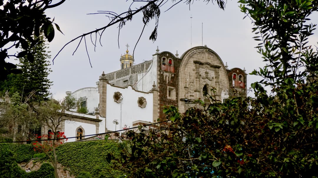 Low-angle view of the Capilla del Cerrito framed by trees on Tepeyac Hill.