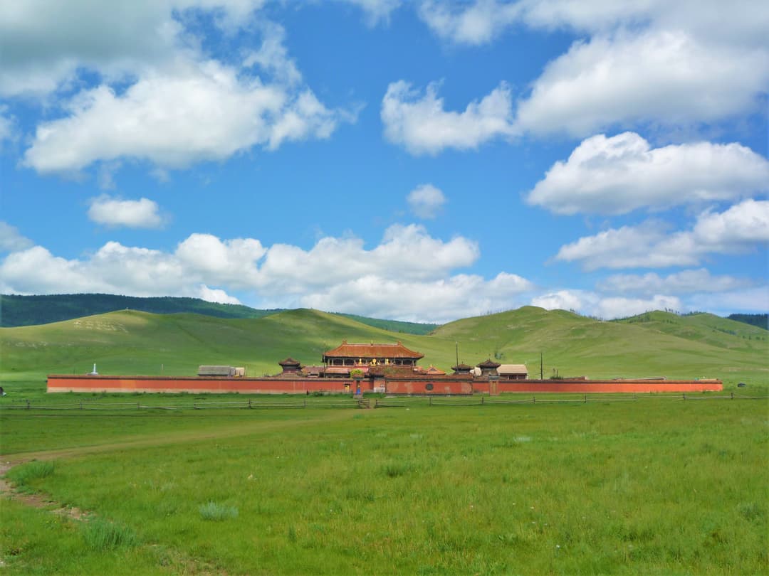 Distant wide view of Amarbayasgalant Monastery set against green rolling hills.