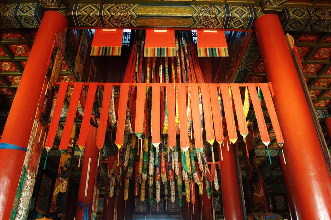 Interior view of the temple hall with red columns and hanging silk banners.