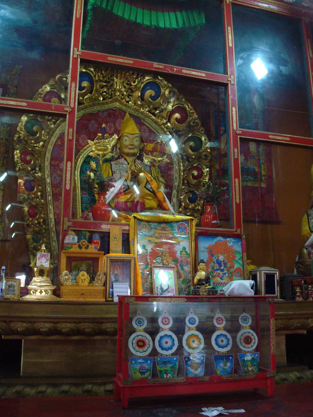 Interior view of a temple shrine with a Gelug Lama statue and offerings.