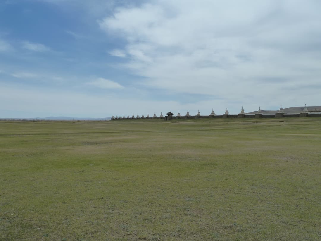 Distant wide-angle view of the stupa-lined perimeter wall across the steppe.