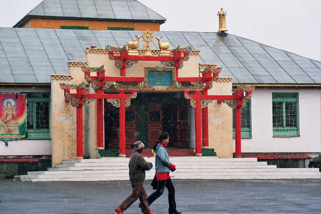 Front entrance view of a Gandan Monastery temple building during snowfall.