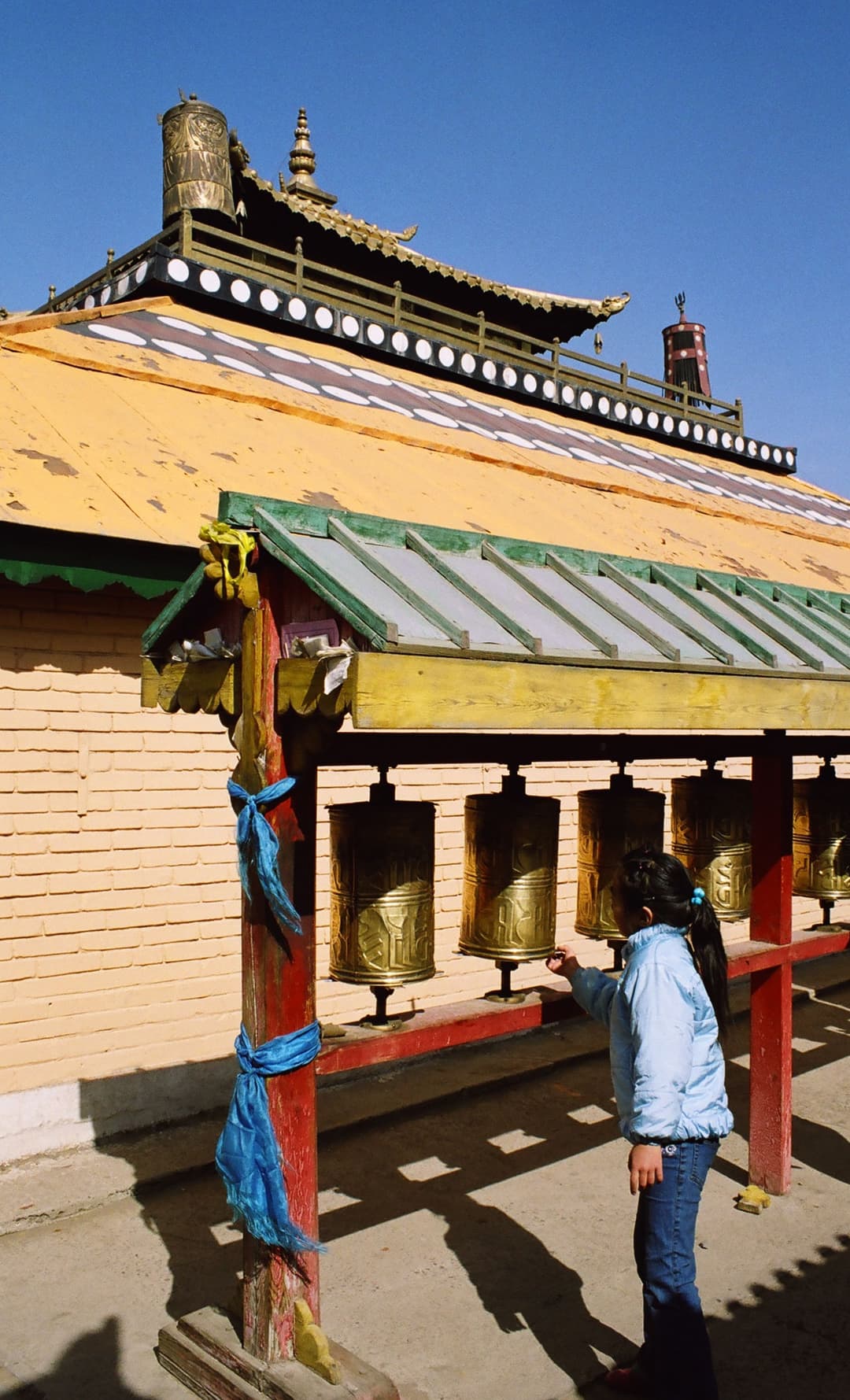 A young girl turning golden prayer wheels at Gandantegchinlen Monastery.