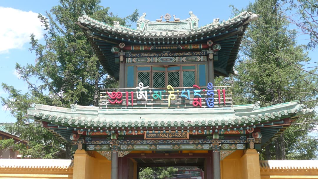 Front view of an ornate entry gate displaying Tibetan script at Gandan Monastery.