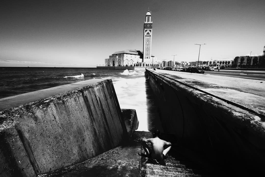 Black-and-white view of Hassan II Mosque from the coastal seawall.