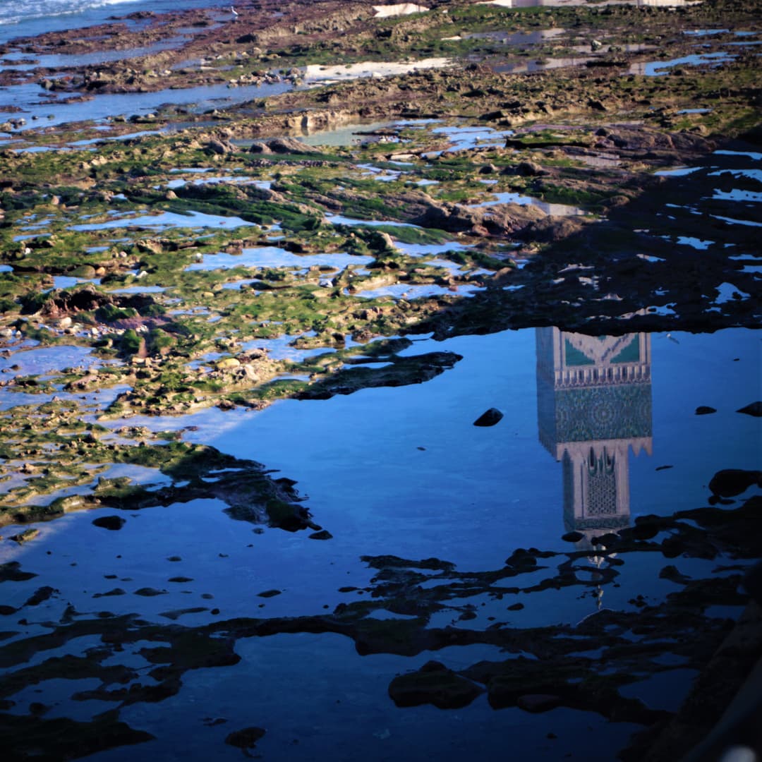 Reflection of the Hassan II Mosque minaret in a coastal tide pool.