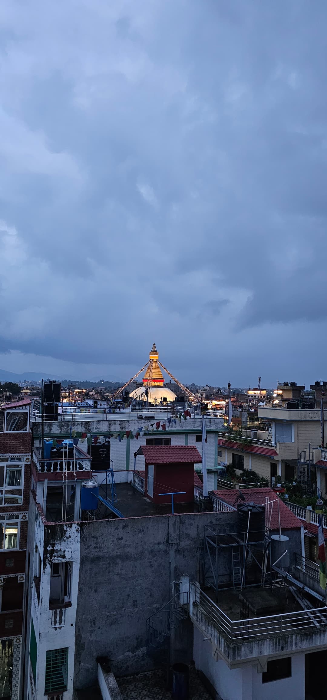 Rooftop view of the illuminated Boudhanath Stupa at twilight.
