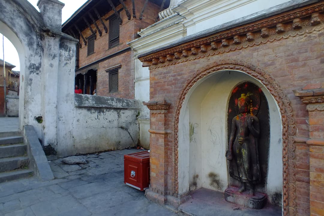 Licchavi-era standing Buddha statue in a brick niche at Pashupatinath