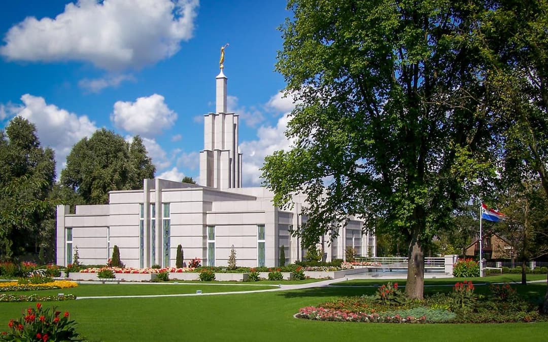 Wide daytime view of The Hague Netherlands Temple and its manicured gardens.