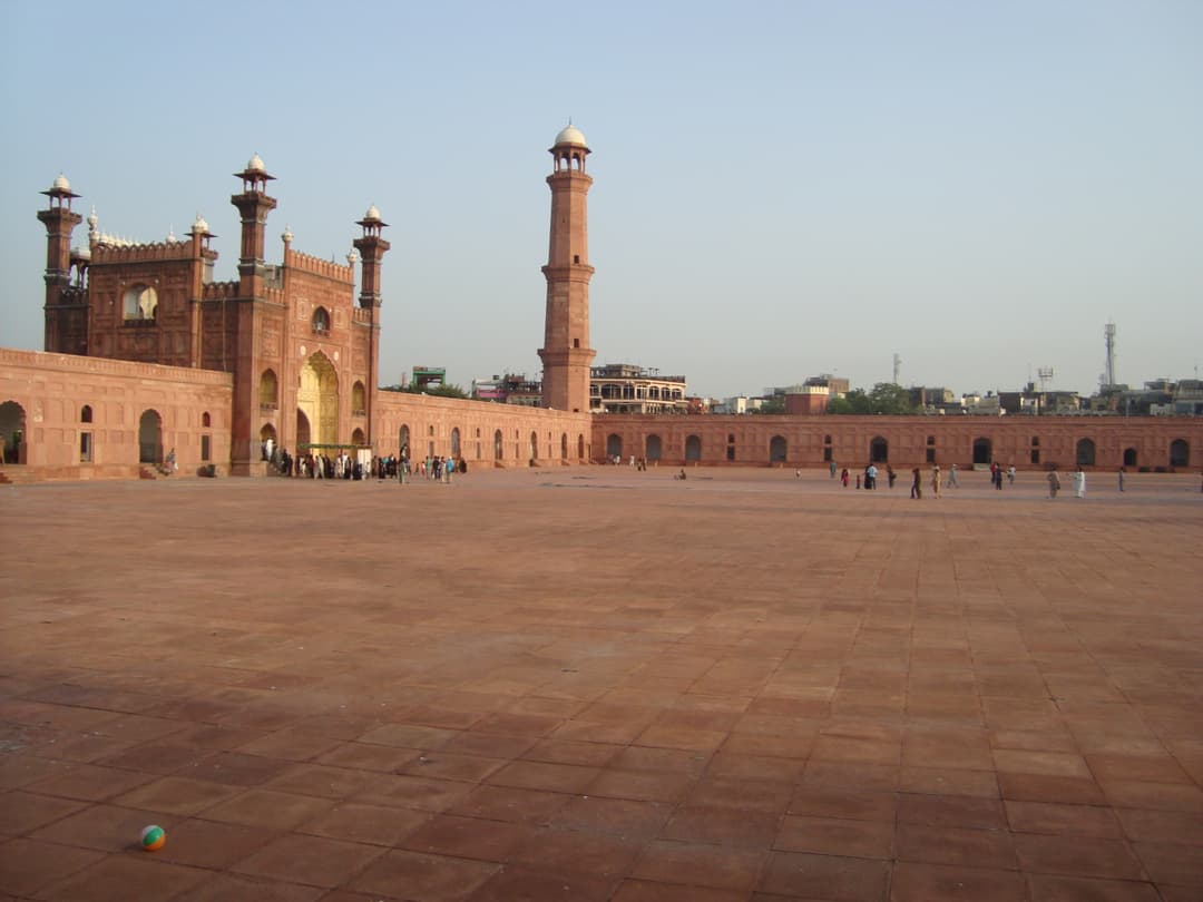 View across the vast courtyard toward the main entrance gate and minaret.