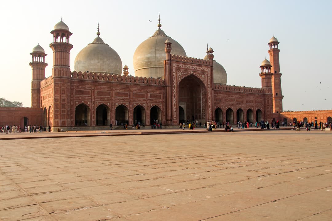 Main prayer hall and marble domes across the vast Badshahi Mosque courtyard