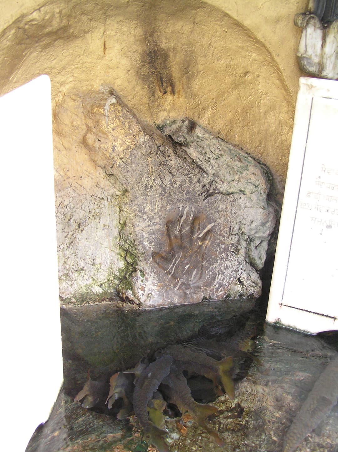 Sacred boulder bearing Guru Nanak's handprint above the spring pool