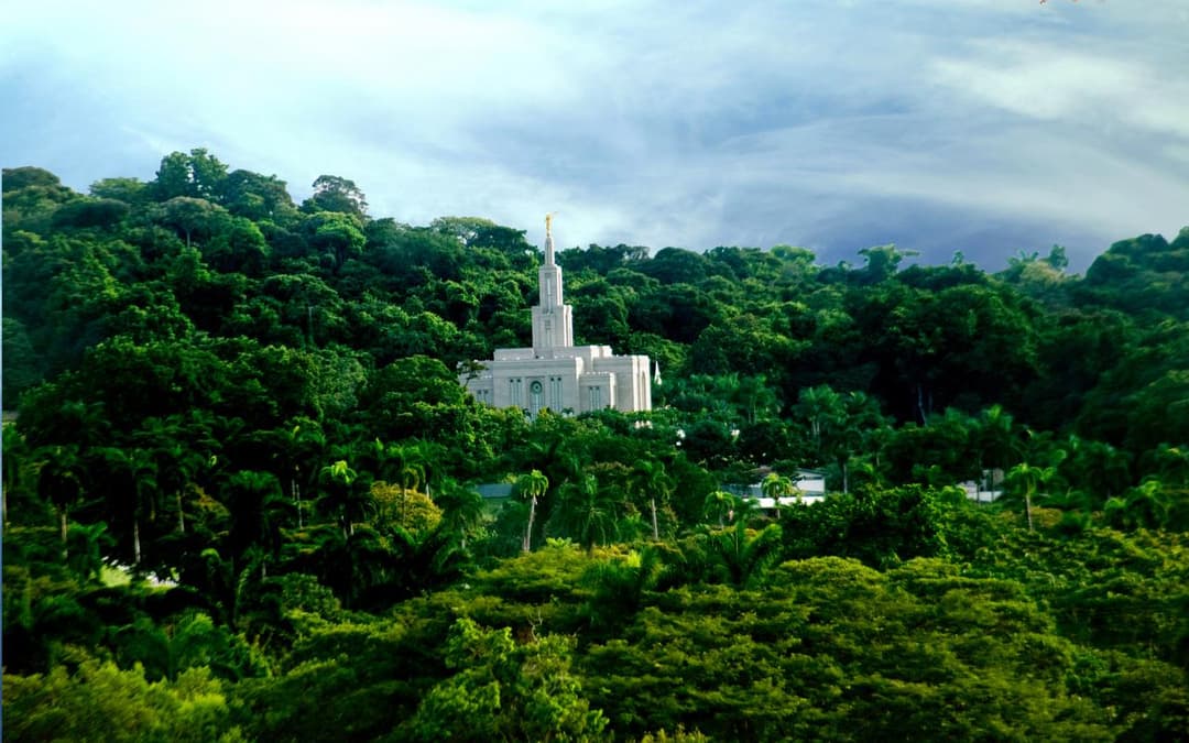 Daytime exterior of Panama City Panama Temple amidst tropical greenery.