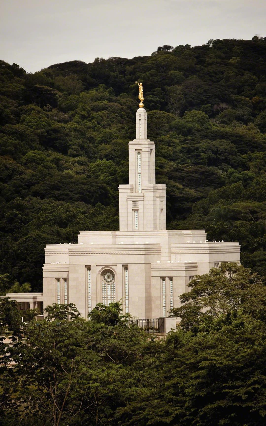 Panama City Panama Temple's spire and facade, partially obscured by trees.