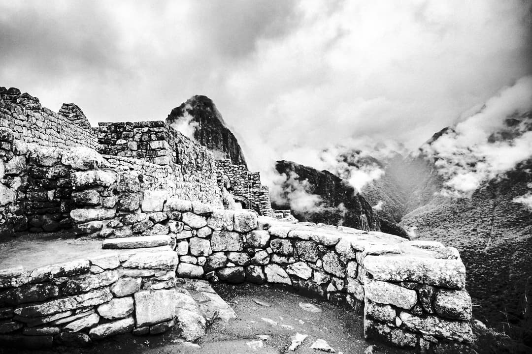 Inca stone walls with Huayna Picchu shrouded in mist.