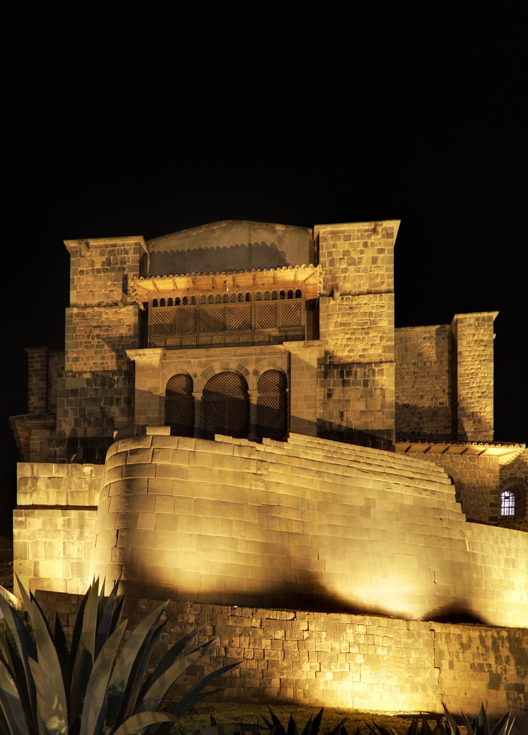 The curved Inca wall and Santo Domingo illuminated at night
