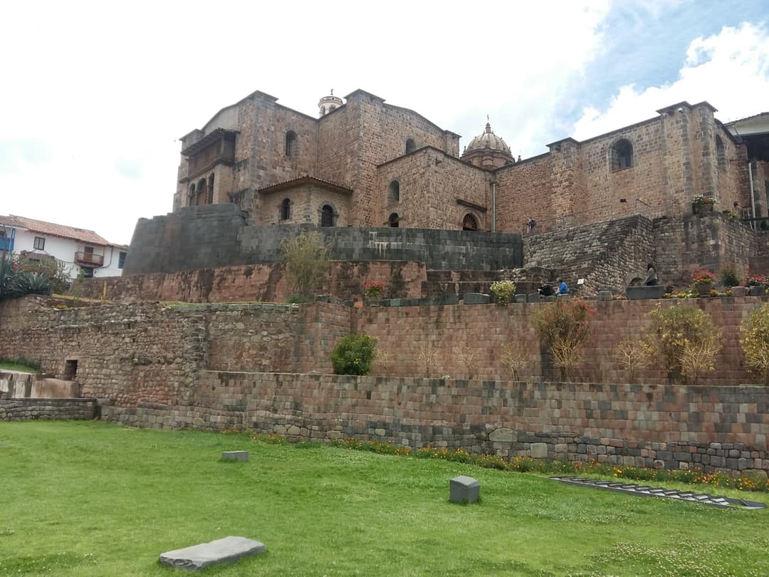 View of Qorikancha's curved Inca wall and Santo Domingo from the gardens