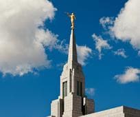 Low-angle daytime view of the temple spire and Angel Moroni statue.