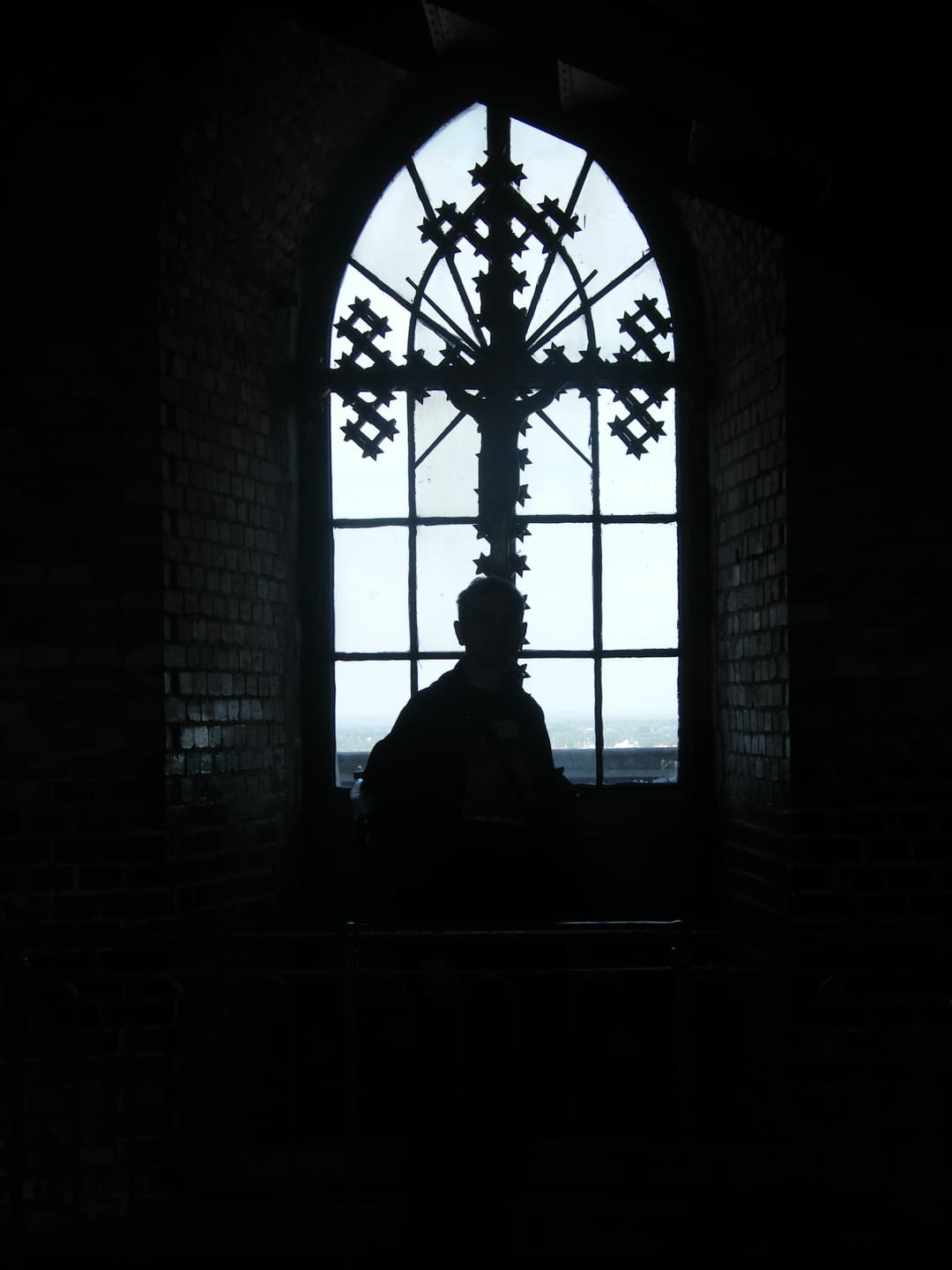Silhouette before an ornate cross window in the Jasna Góra tower