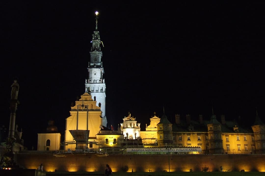 Jasna Góra Monastery complex and bell tower illuminated at night.