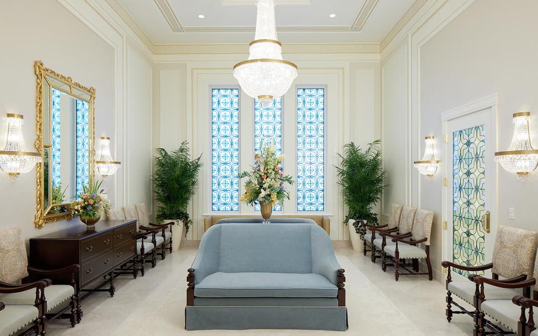 Interior waiting area with crystal chandelier and blue sofa.