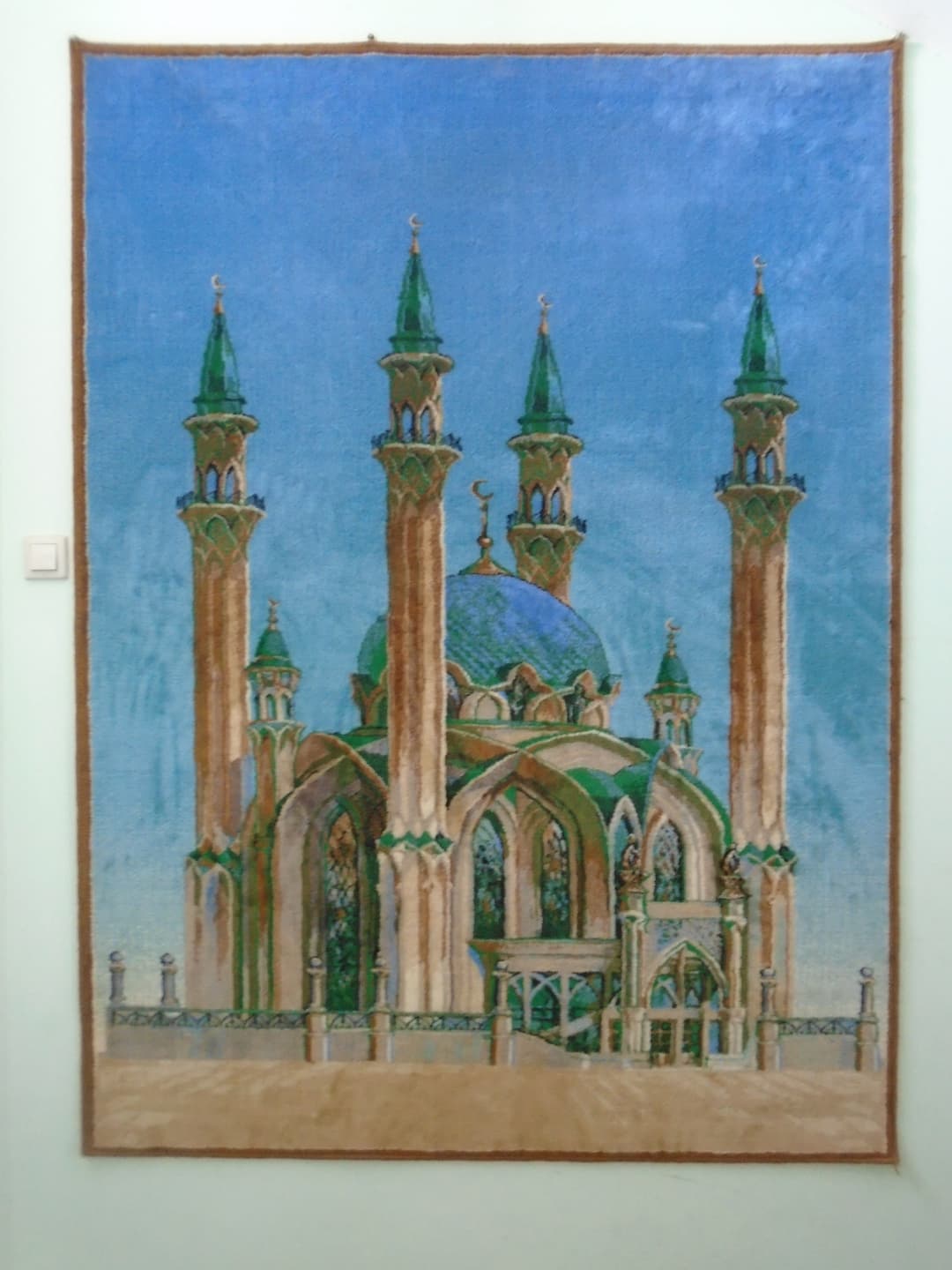 Tapestry depicting the Kul Sharif Mosque hanging on a wall.