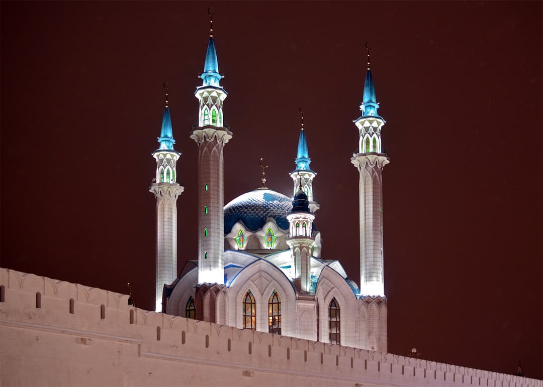 Kul Sharif Mosque minarets and dome over the Kremlin wall at night.