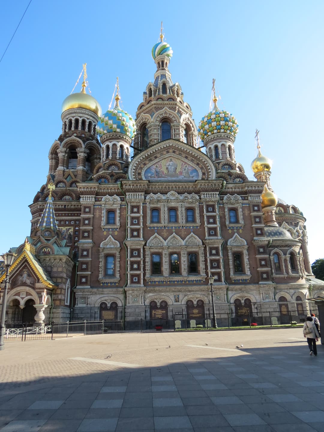 Low-angle view of the ornate facade and colorful onion domes in daylight.