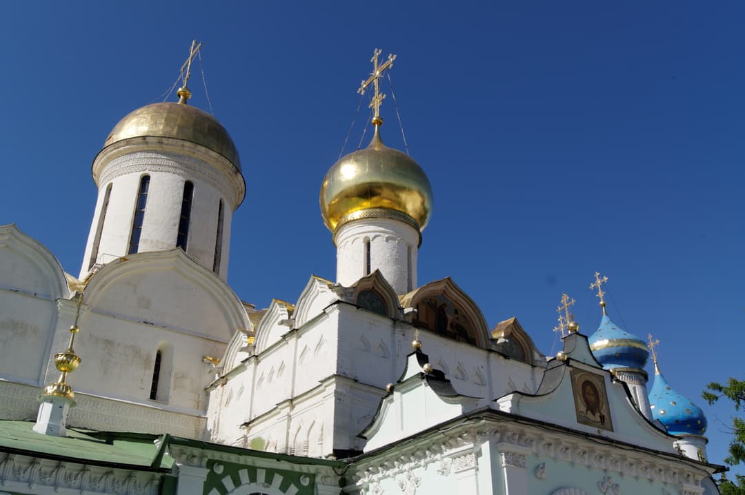 Golden domes of Trinity Cathedral and Nikon Church against a blue sky.